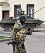 Armed men wearing military fatigues on Wednesday gather near armored vehicles as they guard a regional state building seized by pro-Russian separatists in the eastern Ukrainian city of Slavyansk. A former U.S. government analyst said a broader Russian invasion of Ukraine could disrupt operations at nuclear reactors.