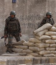 Syrian government army soldiers stand behind sandbags in a Damascus suburb last month. Syria asked for consideration of its "delicate situation" following an International Atomic Energy Agency request for cooperation in the investigation of the country's suspected illicit nuclear activities (AP Photo/Muzaffar Salman).