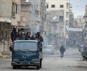 Syrian opposition fighters ride a truck through the town of Deir Ezzor on Monday. Rockets this week reportedly struck a Syrian coastal city where President Bashar Assad's government is turning over chemical-warfare materials for destruction by other governments.