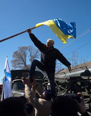 A pro-Russian protester takes down a Ukrainian flag as activists storm a Ukrainian air base in western Crimea on Saturday. The House Foreign Affairs Committee on Tuesday approved a Russia-sanctions bill with language that may lead to tightened penalties against Iran's supporters.